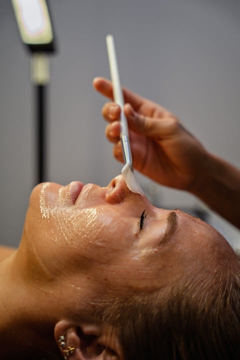 Person receiving a facial treatment with a white applicator being applied to their forehead and face