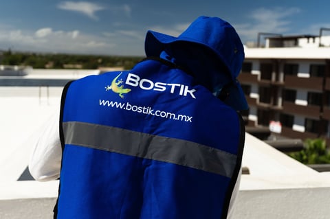 Blue Bostik work vest with reflective strip hanging on construction site roof with cityscape background