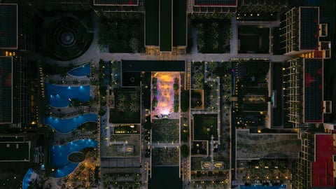 Aerial night view of urban cityscape with illuminated buildings, green courtyards, and streets from above